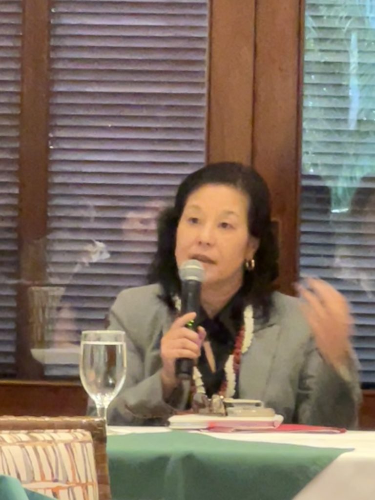 Commissioner Kuwaye holding a microphone.