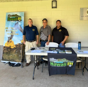 Two PUC employees and one Hawaiʻi One Call Center consultant stand behind a Hawaii 811 outreach table during the Spring 2026 HOCC seminar on Oʻahu. The table features informational materials and signage promoting the “Call Before You Dig” 811 program and safe excavation practices.